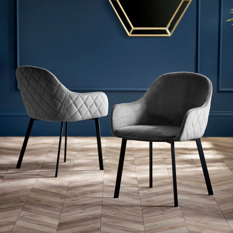 Two gray chairs with quilted backrests on a wooden floor against a blue wall.