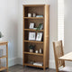 Wooden bookshelf with decorative items in a room with a chair and table.