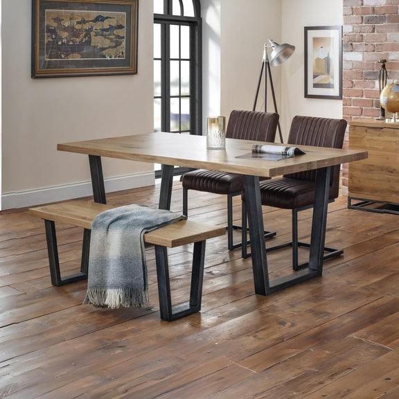 Dining area with wooden table, chairs, and bench on a wooden floor.