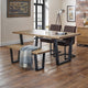 Dining area with wooden table, chairs, and bench on a wooden floor.