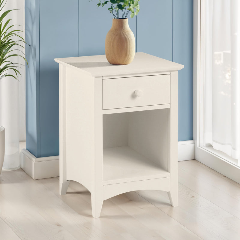 White nightstand with a vase and plant against a blue wall