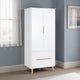 White wardrobe with wooden legs in a room with a window and framed picture on the wall.