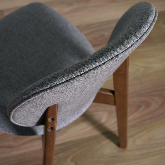 Gray upholstered chair with wooden legs on a wooden floor