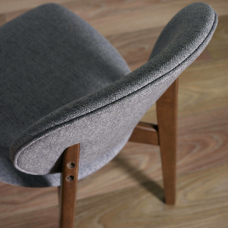 Gray upholstered chair with wooden legs on a wooden floor