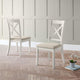 Two white chairs with beige cushions on a wooden floor against a paneled wall.
