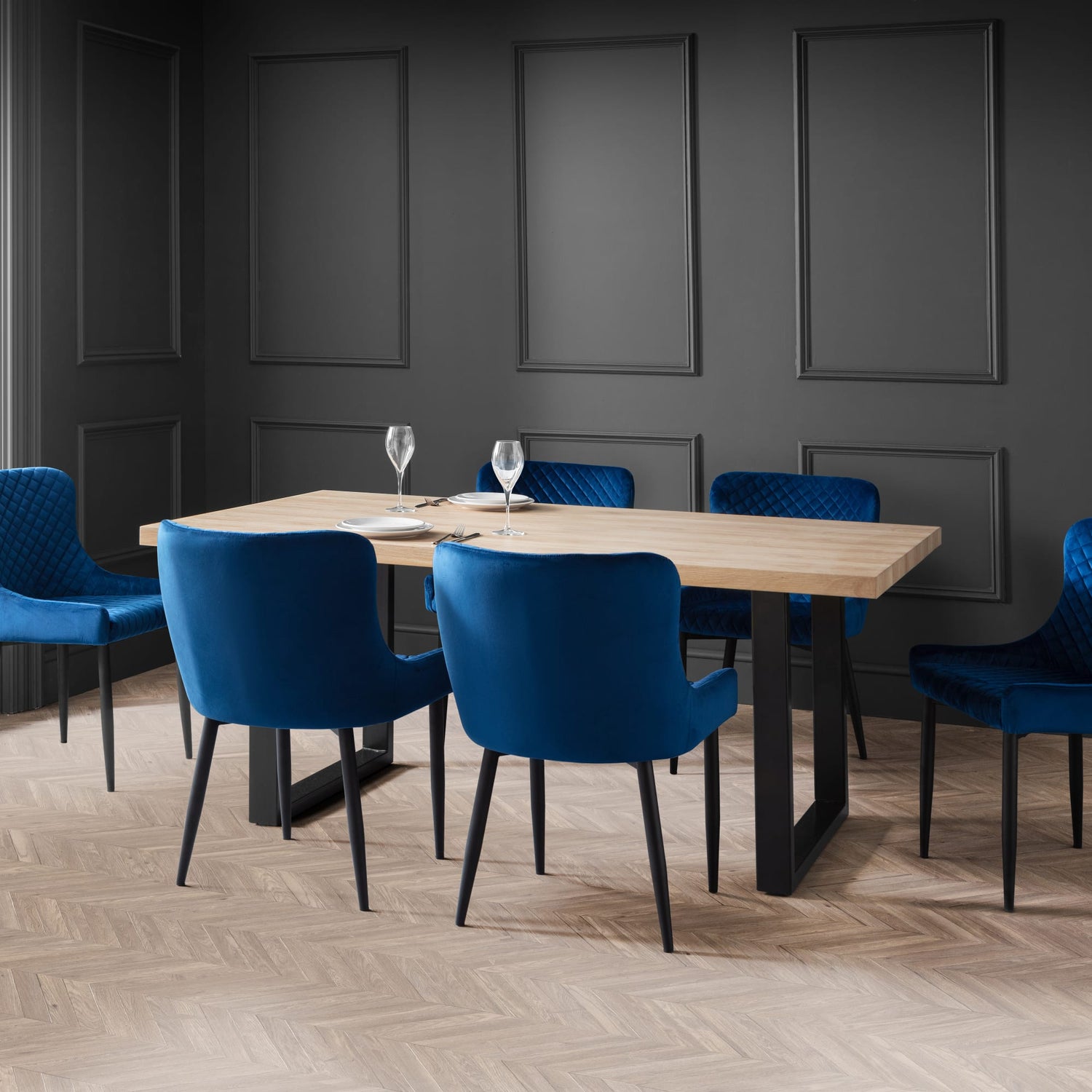 Dining room with a wooden table and blue chairs against a dark gray wall.