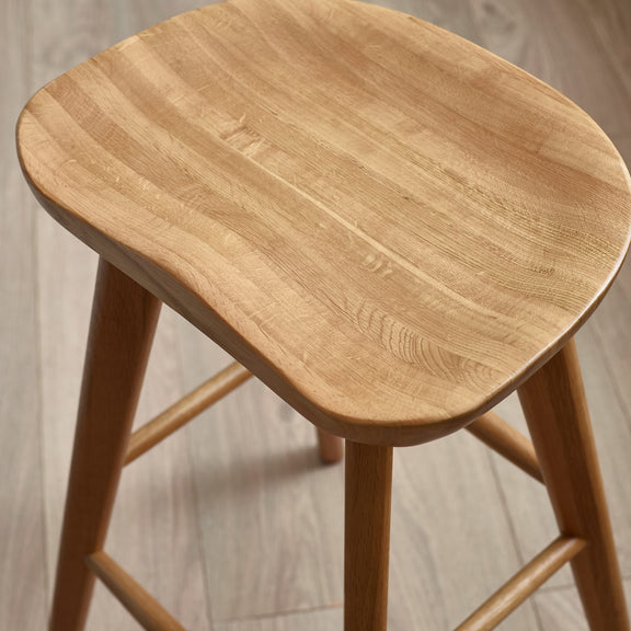 Wooden stool with a light brown finish on a neutral background