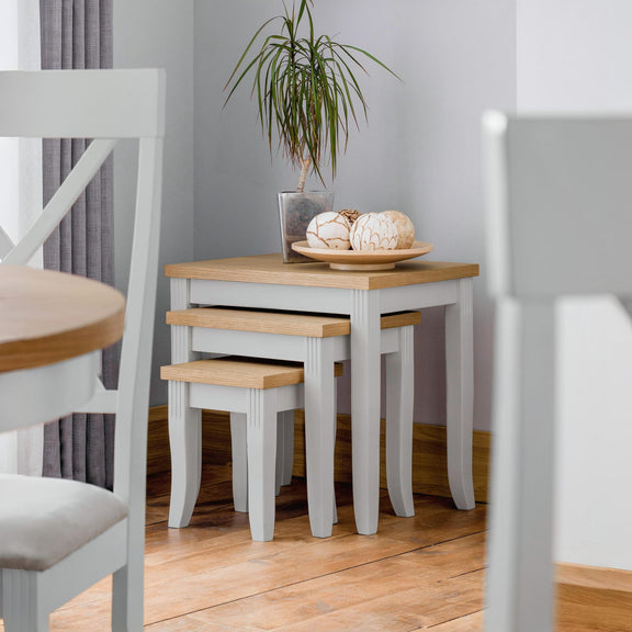 Dining area with wooden table, chairs, and a plant in a room with light gray walls.