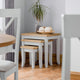 Dining area with wooden table, chairs, and a plant in a room with light gray walls.