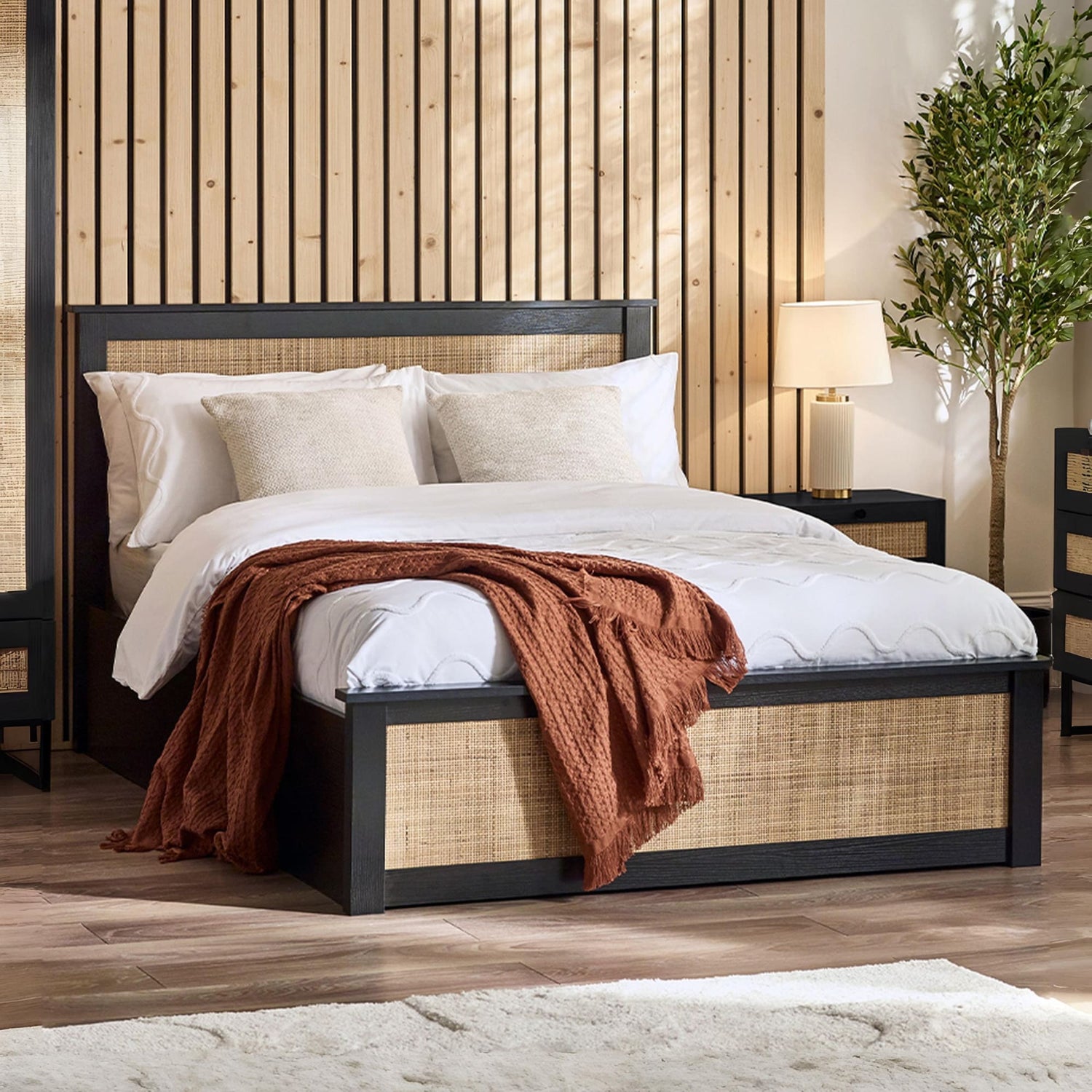 Bedroom with a bed featuring white bedding and a brown blanket, against a wooden paneled wall.