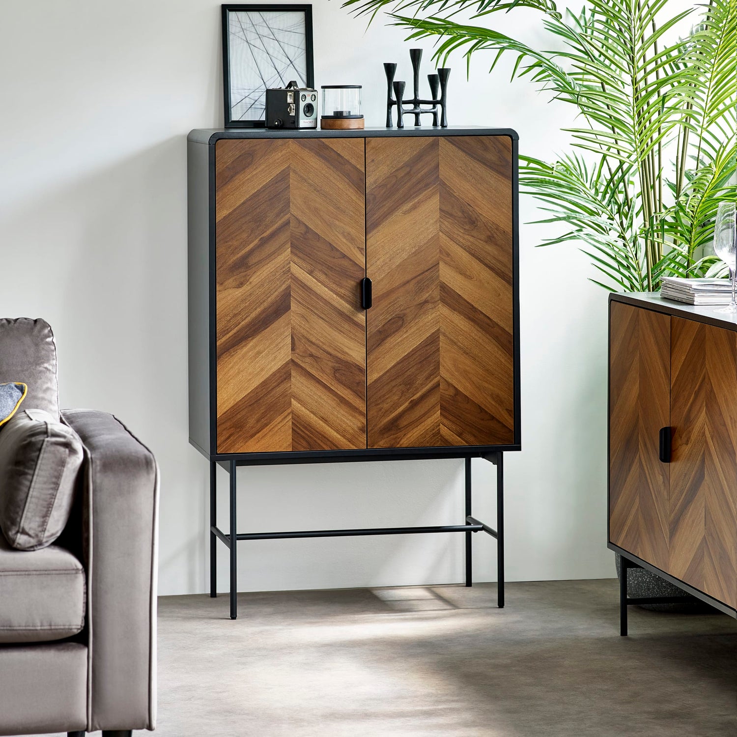 Wooden cabinet with chevron pattern in a room with a gray sofa and plant