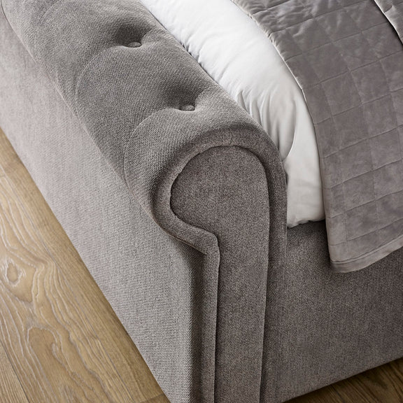 Gray upholstered bed with tufted headboard on a wooden floor
