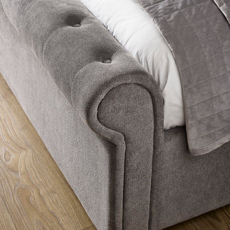 Gray upholstered bed with tufted headboard on a wooden floor