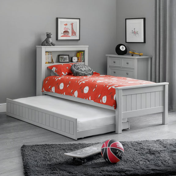 Children's bedroom with a white bed with red bedding and a gray wall.