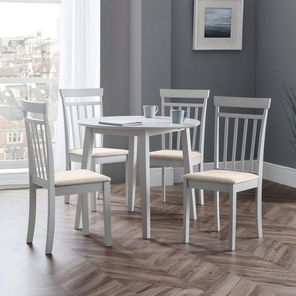Dining room with a round table and four chairs on a wooden floor.