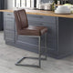 Brown leather bar stool in front of a kitchen island with gray cabinets.