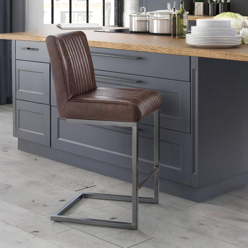 Brown leather bar stool in front of a kitchen island with gray cabinets.