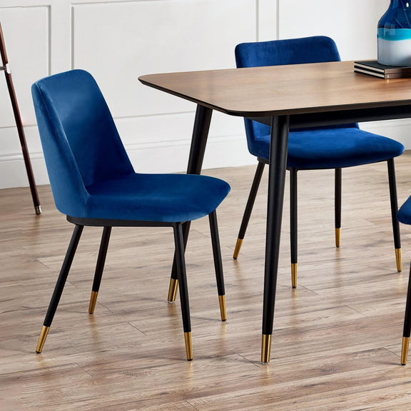 Blue chairs with gold legs around a wooden table on a wooden floor.