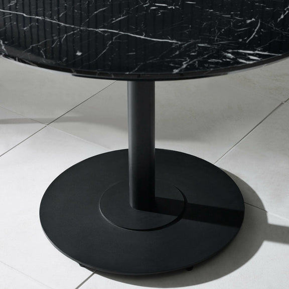 Black round table with marble top on a light gray floor