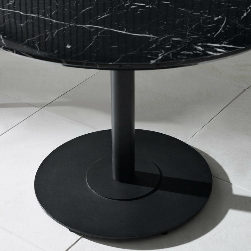 Black round table with marble top on a light gray floor