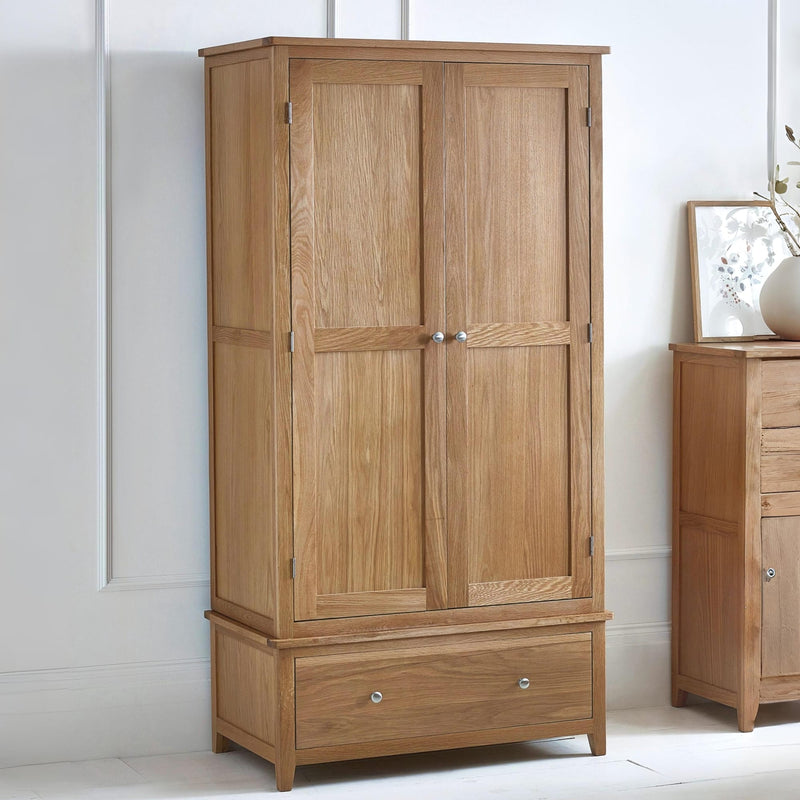 Wooden wardrobe with two doors and a drawer in a room setting.