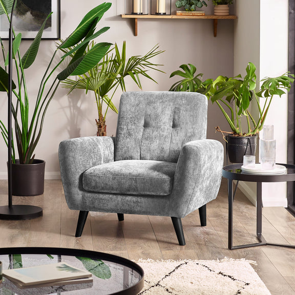 Gray armchair in a living room with plants and a coffee table.