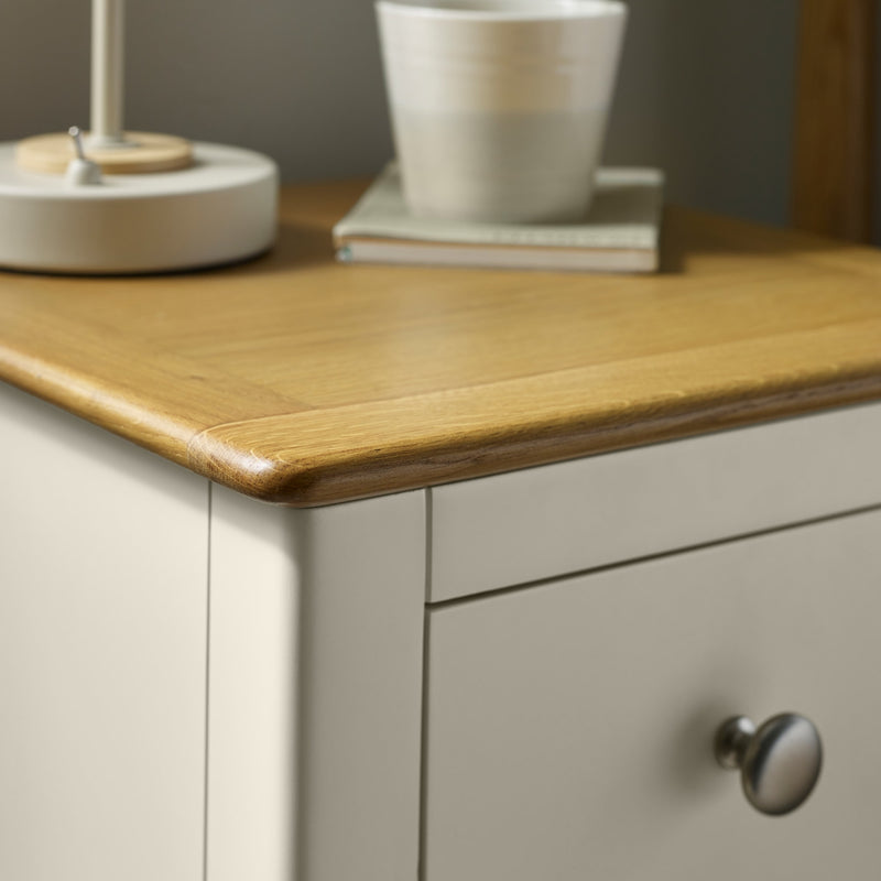 Close-up of bedside table drawer with round metal knob and oak top