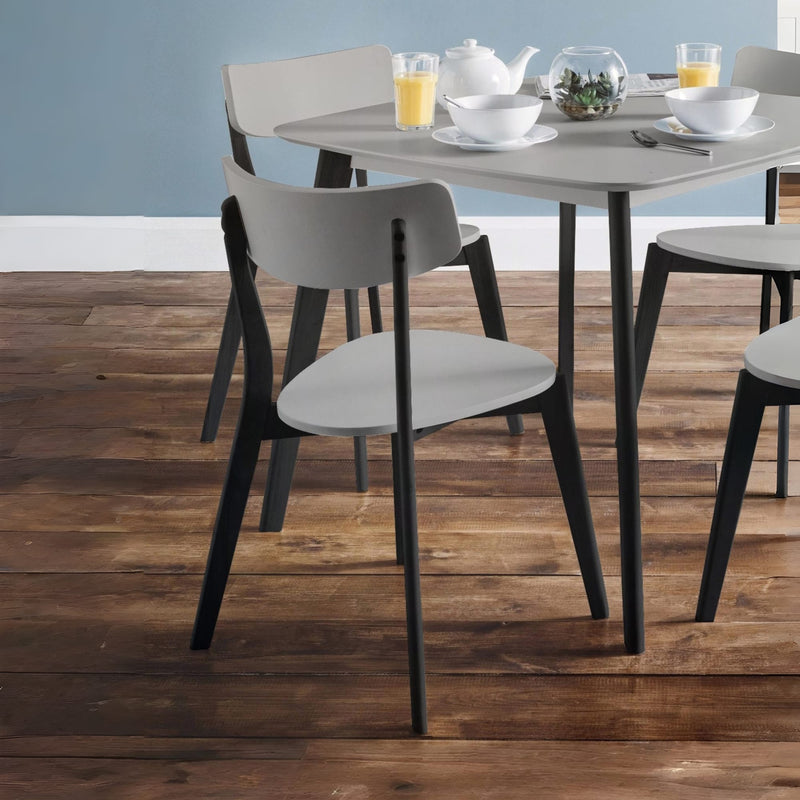Dining table with chairs on a wooden floor against a light blue wall.