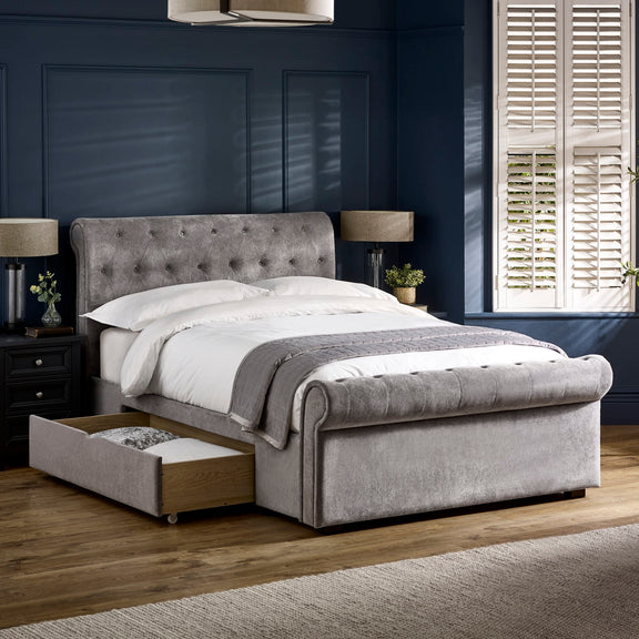 Gray upholstered bed with storage drawers in a bedroom setting.