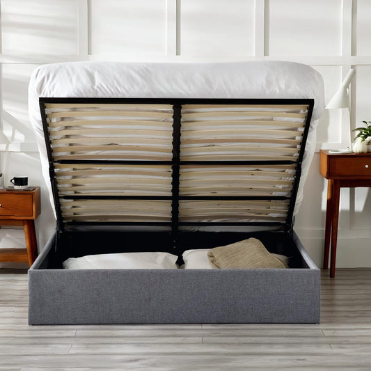 Gray upholstered bed with open headboard showing mattress and support system in a bedroom setting.