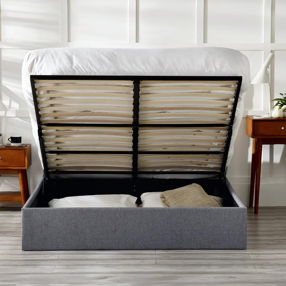 Gray upholstered bed with open headboard showing mattress and support system in a bedroom setting.