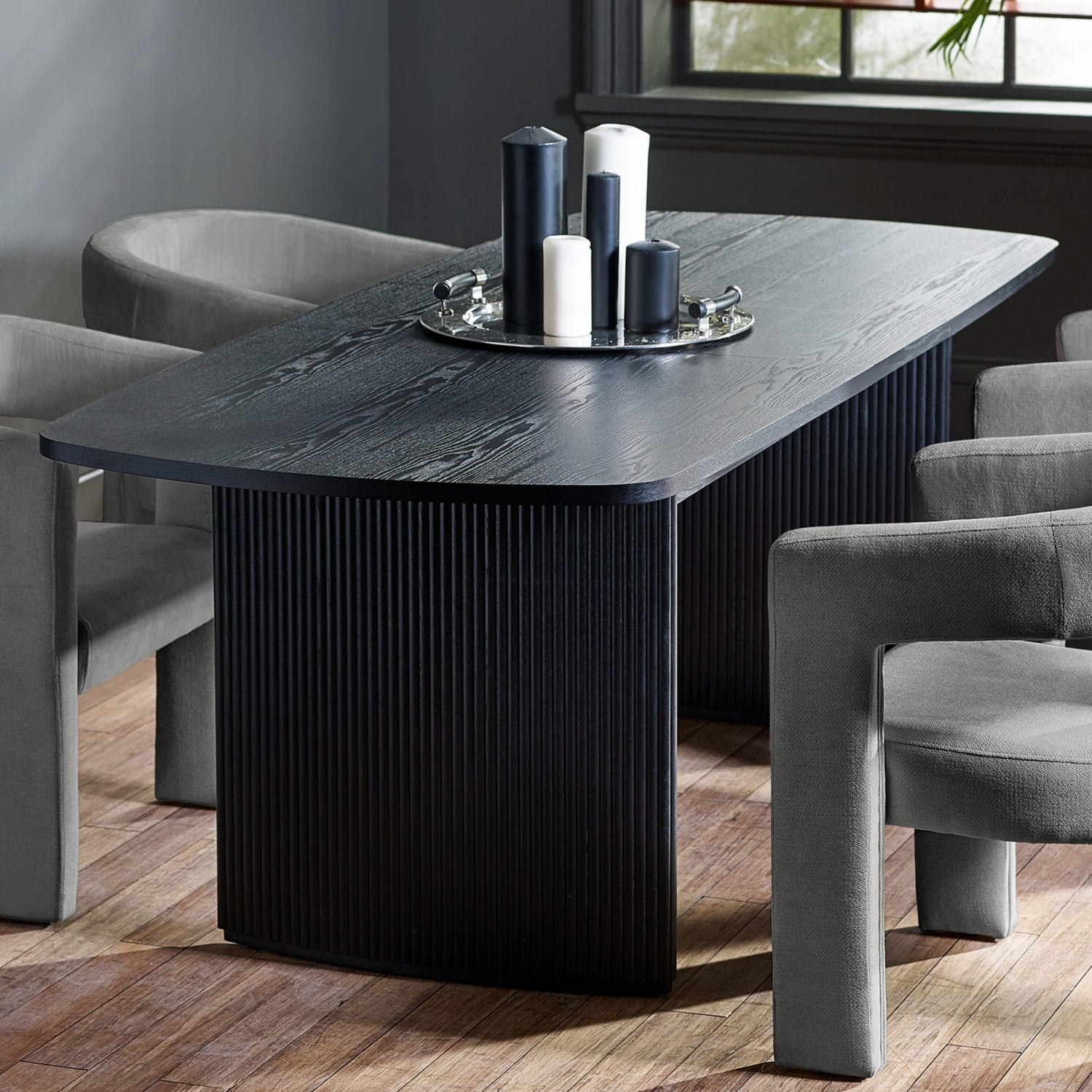 Black dining table with decorative items in a room with gray chairs.