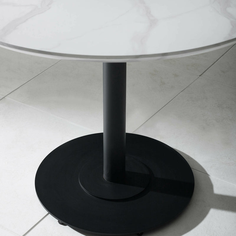 Round glass table with a black metal base on a tiled floor