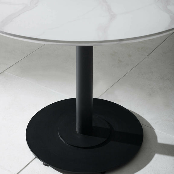 Round glass table with a black metal base on a tiled floor