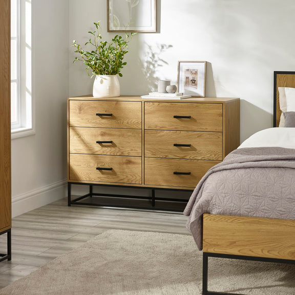 Wooden dresser with four drawers in a bedroom setting.