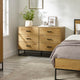 Wooden dresser with four drawers in a bedroom setting.