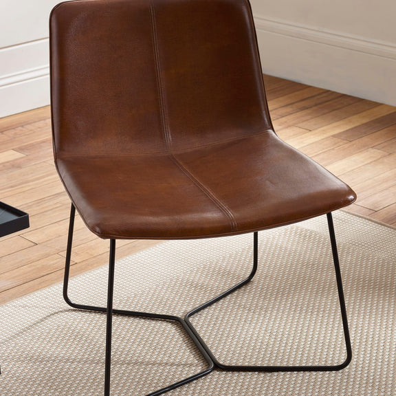 Brown leather chair with black metal legs on a wooden floor.