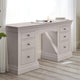 Light gray desk with multiple drawers in a room with white curtains.