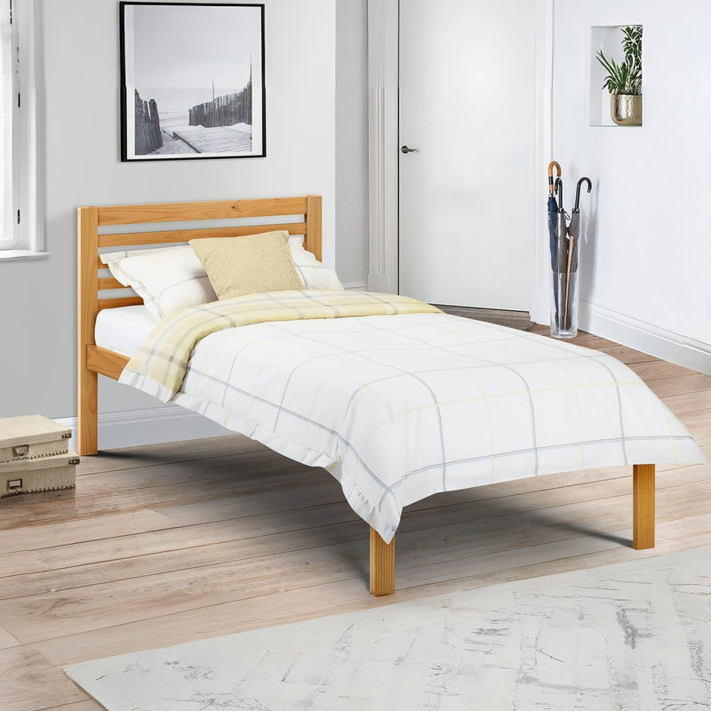 Wooden bed with white bedding in a room with a door and plant