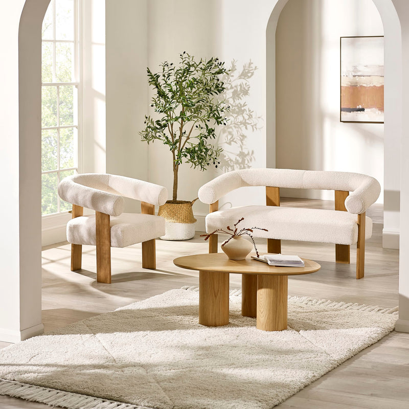 Modern living room with white armchairs, a wooden coffee table, and a plant.
