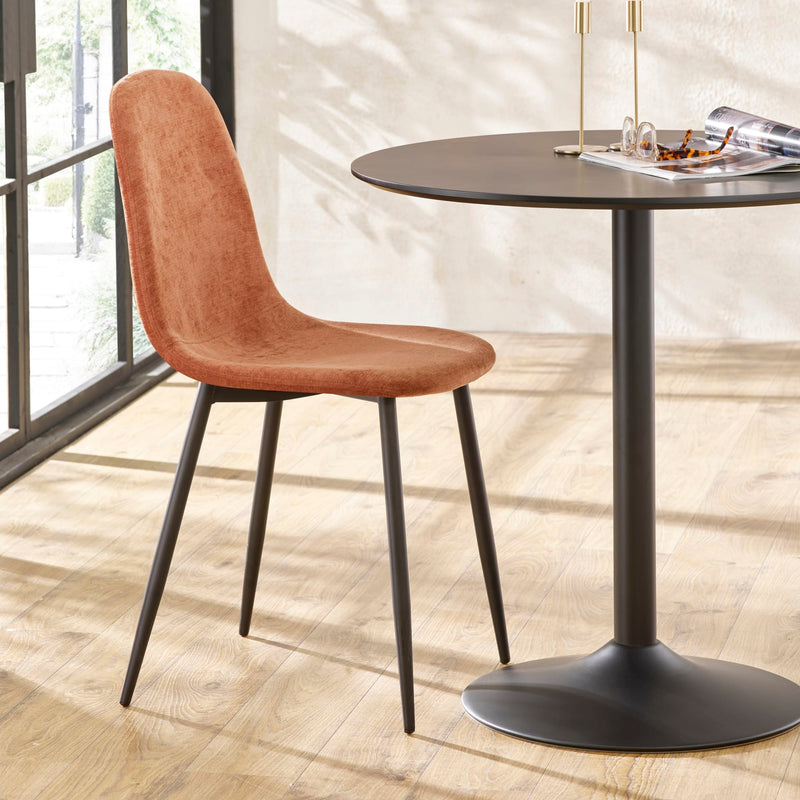 Brown chair next to a black round table on a wooden floor.