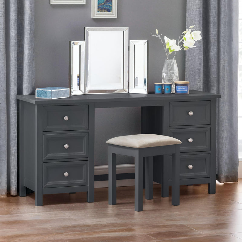 Gray vanity desk with mirror, drawers, and stool in a room with gray curtains.