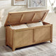 Wooden storage bench with open lid revealing white cushions in a room setting.