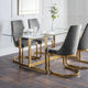 Dining table with glass top and gold legs accompanied by gray chairs in a modern setting.