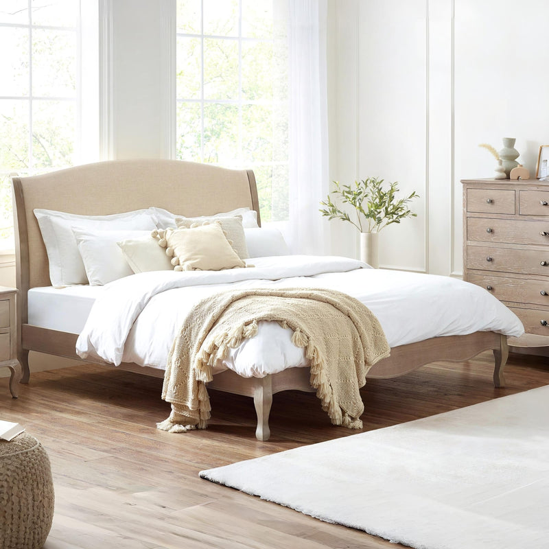 Neatly made bed with beige blanket in a bright bedroom