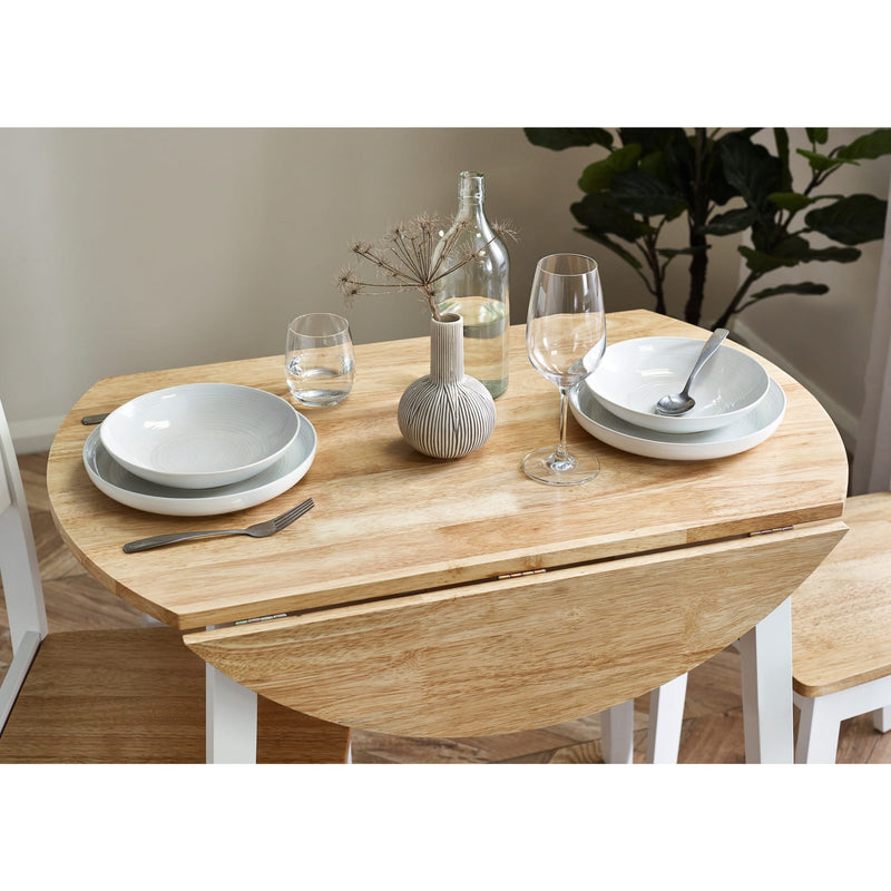 Dining table set with plates, glasses, and a vase on a wooden table.