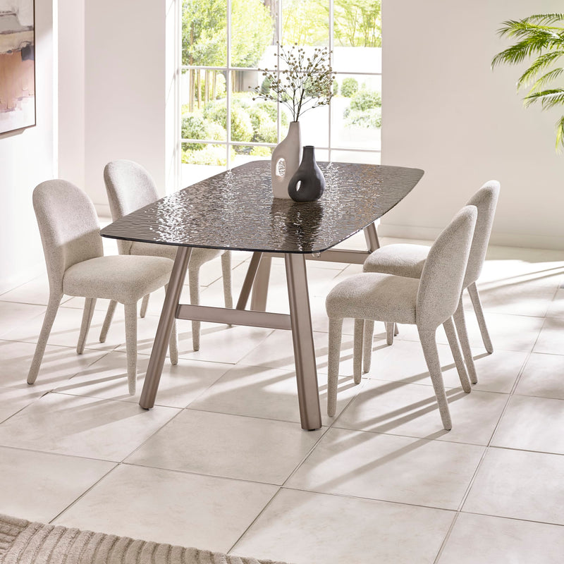 Dining table with four chairs in a bright room with large windows.