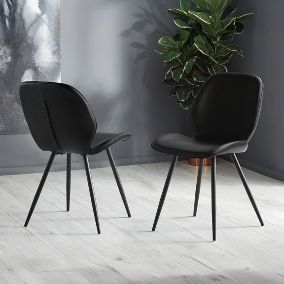 Two black chairs on a light wooden floor with a plant in the background.