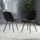 Two black chairs on a light wooden floor with a plant in the background.