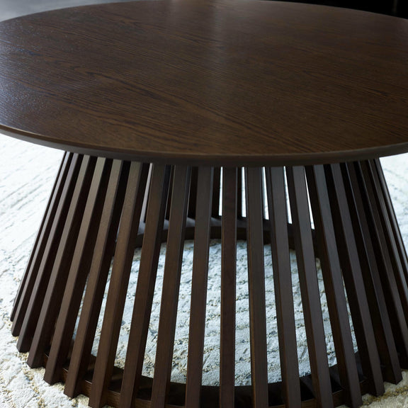 Round wooden table with slatted base on a textured surface